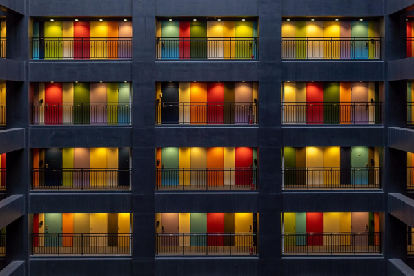 Image shows four floors of apartments with doors of bright colors