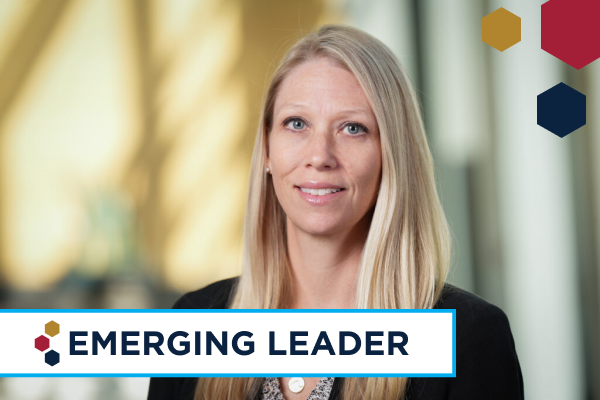 Rebecca McNally Keehn smiles in her headshot. She is a fair skinned blonde woman and wears a dark blazer. In the foreground left corner of the image is a banner reading 'Emerging Leader' and the Indiana CTSI's hexagon logo.