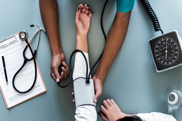 A person takes blood pressure from another using a blood pressure cuff.