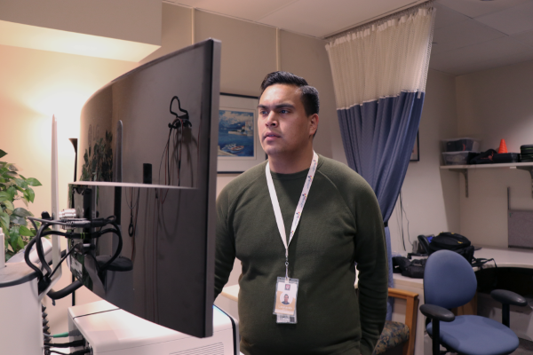 Leonardo Alarcon stands in an office and looks at a computer screen.