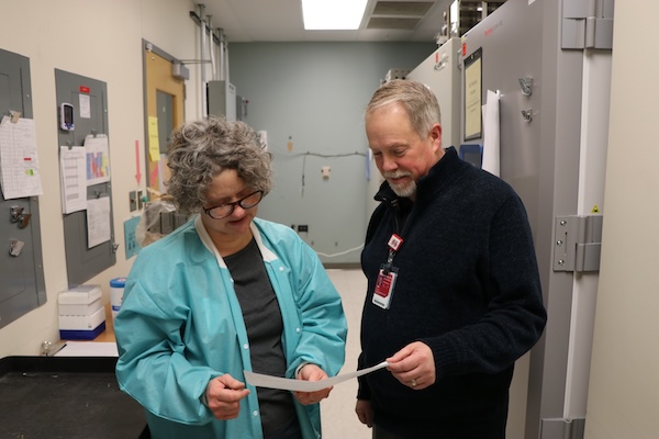 Jenna York and Rob Orr consult a document together in a freezer room.