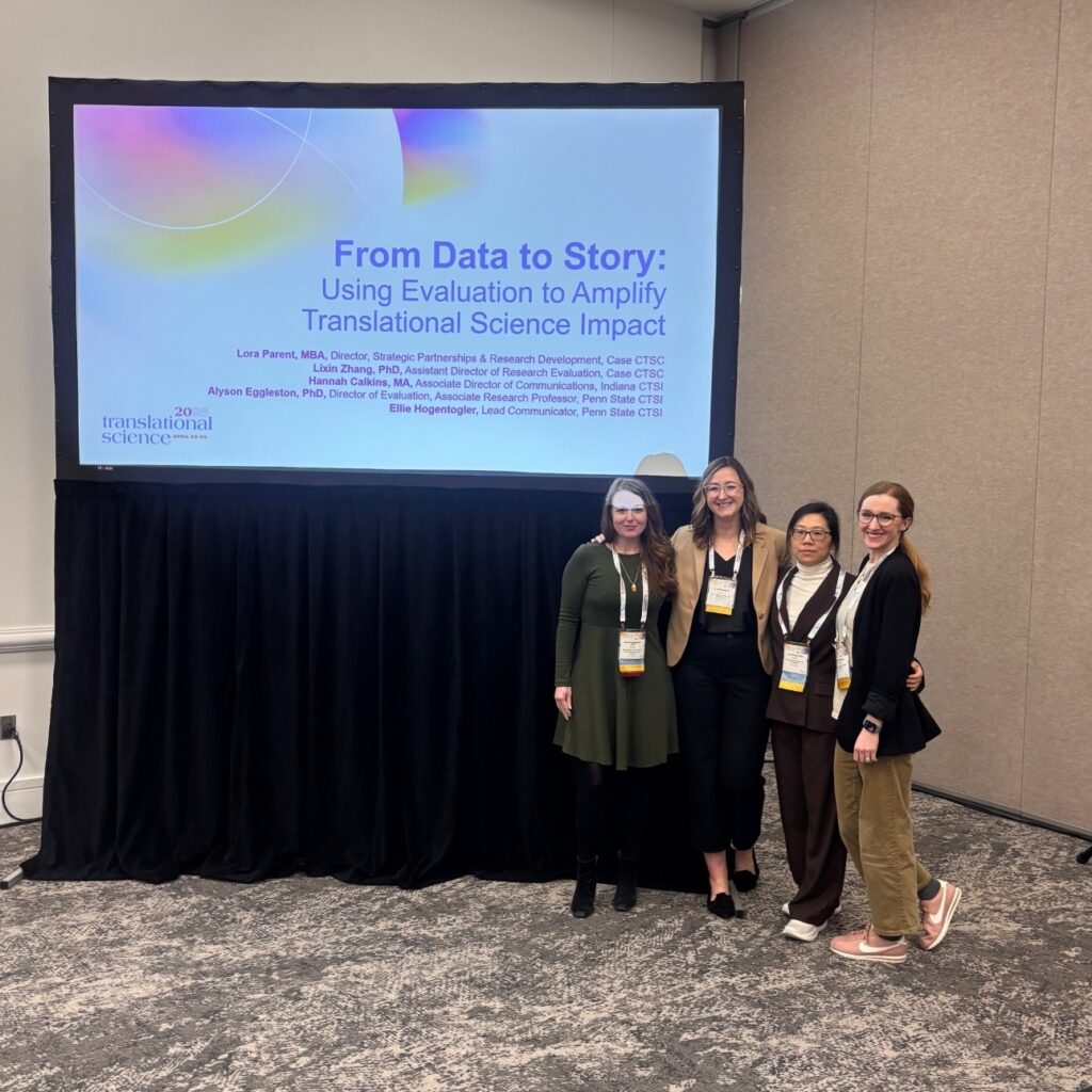 Four presenters pose in front of presentation screen.