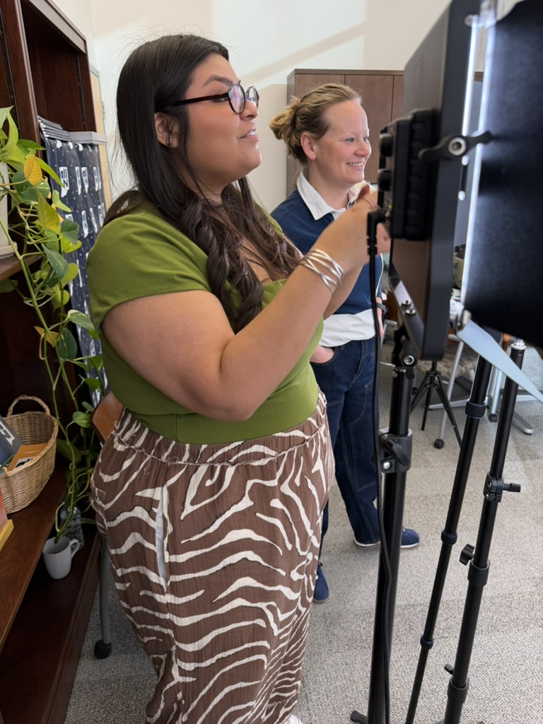 Bonnie Marcelo gives direction while standing next to lighting rigs. Lynsey Delp next to her smiling.