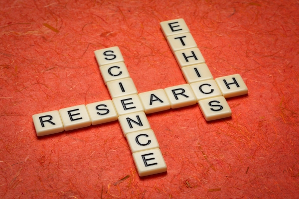 scrabble tiles are laid out on a red background. They spell out the words research, science, and ethics.