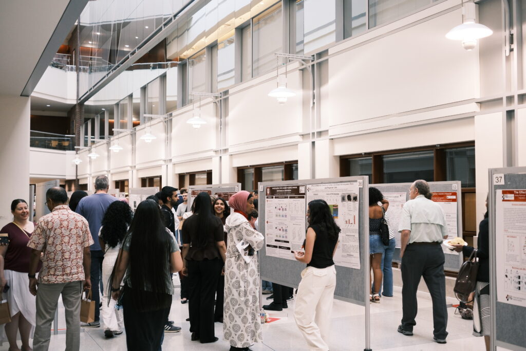 People view posters and speak to each other at the research poster symposium.