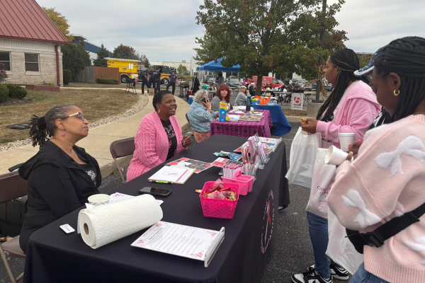 Members of Pink-4-Ever Breast Health Advocates engage with community members at an outdoor festival.