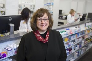 Dr. Karen Hudmon standing in front of a pharmacy window