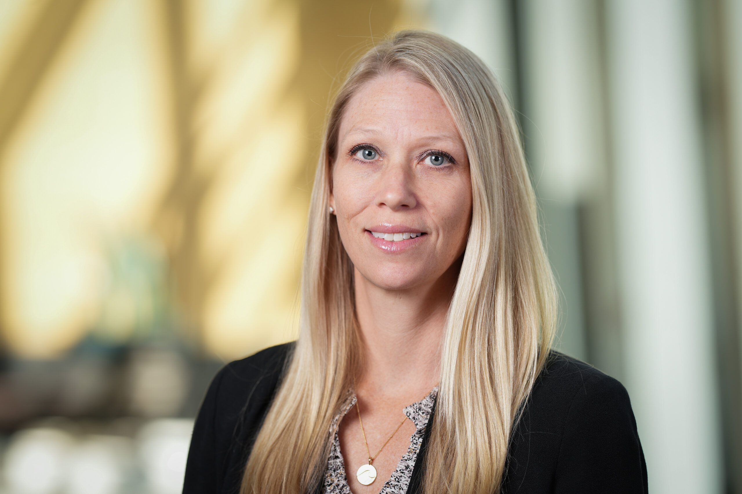 Rebecca McNally Keehn, a thin white woman with blonde hair, smiles in her headshot. She is wearing a black blazer.