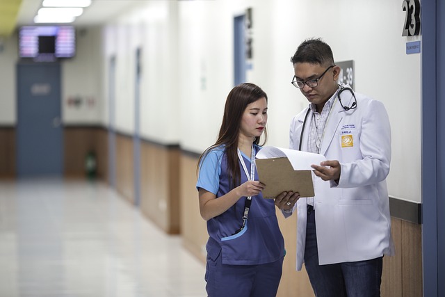 Picture shows a doctor and nurse comparing a chart in a hospital hallway