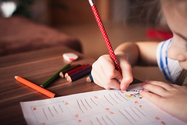 Image shows a child coloring in a work book