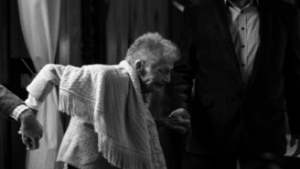 elderly woman being assisted as she stands