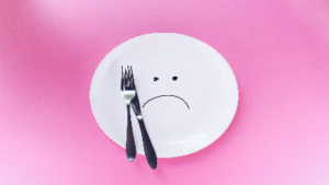 photo of empty plate with sad face and fork and knife