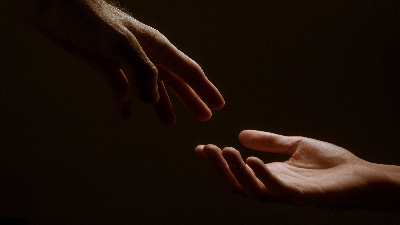 photo of one person's hand reaching for another person's hand