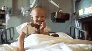 bald child smiles from hospital bed